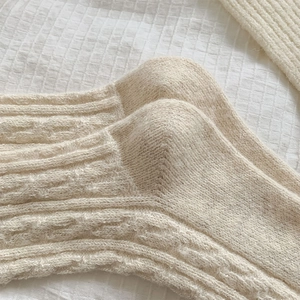 Close-up of thick cream knit wool socks with shimmering metallic yarn detail