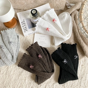 Detailed view of rib knit wool socks featuring cute bow embroidery and ruffled edge cuffs