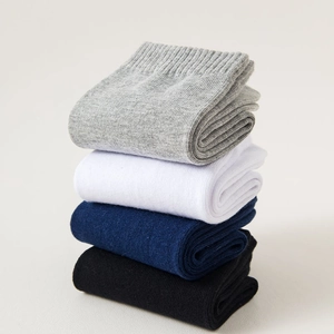 Close-up of four stacked cotton crew socks in grey, white, navy, and black solid colors