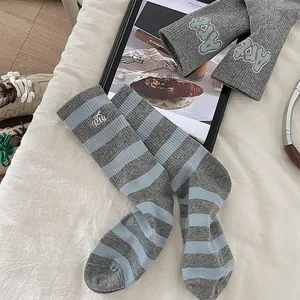Detail of grey ribbed cotton socks with blue stripes and cute embroidered lettering