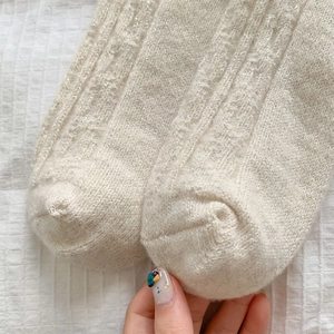 Close-up of off-white knitted socks with silver glitter yarn detail and fine texture