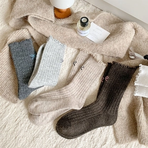 Detailed close-up of wool knit socks with butterfly embroidery and wavy ruffle edges