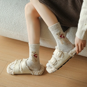 Detail of light grey crew socks with bear embroidery and beige plush double buckle slippers