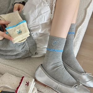 Detail of ballet style socks with bow embroidery, scalloped edges and colorful flecked yarn