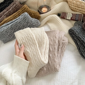 Close-up of thick cable knit wool socks in warm neutral colors on a cozy blanket