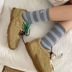 Close-up of khaki suede retro sneaker with green laces and blue striped bear socks