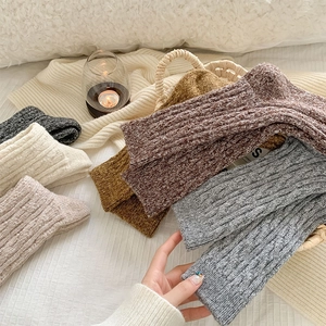 Close-up of thick rib-knitted wool socks in warm neutral colors on a soft blanket