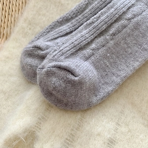 Detail of grey cable knit wool socks showing thick winter texture and seamless toe