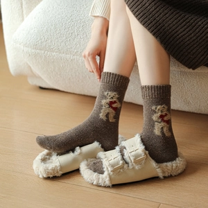 Detail of wool socks featuring a cute brown teddy bear holding a heart on warm knit fabric
