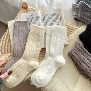 Close-up of thick cable knit wool socks in neutral tones on a cozy vintage background