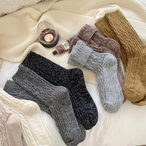 Detailed view of thick cable knit wool socks in various warm earth tones for winter