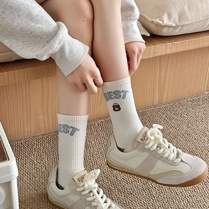 White mid-calf cotton socks with BEST embroidery and bear detail worn with trainers
