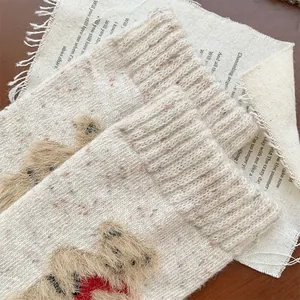 Close-up of cozy knitted wool socks with 3D teddy bear detail and colorful flecks