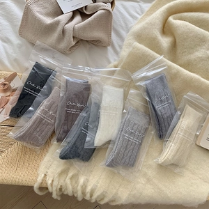 Detail of cable knit wool socks in diverse colors shown in zip-lock gift packaging