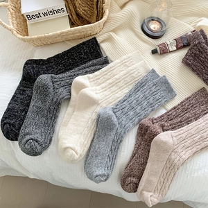 Close-up of thick cable-knit wool socks in various colors showing texture and patterns