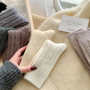 Detail of cable knit wool socks in neutral tones arranged in a cozy setting