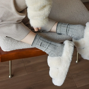 Détail de chaussettes en laine grise à torsades avec broderie de nœud noir délicat