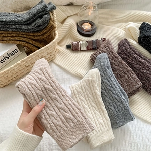 Macro detail of chunky cable knit wool socks featuring thick thermal texture and warm tones