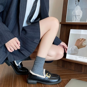 Detail of black loafers featuring warm faux shearling lining and a gold metal buckle