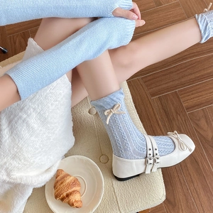 Close-up of light blue knit socks with cream bow and white Mary Jane shoes