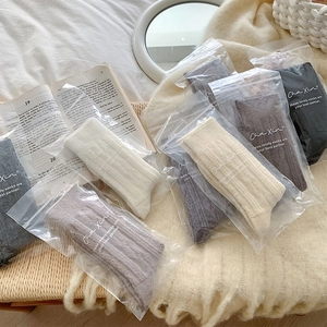 Detail of cable knit wool socks in neutral earth tones with individual packaging