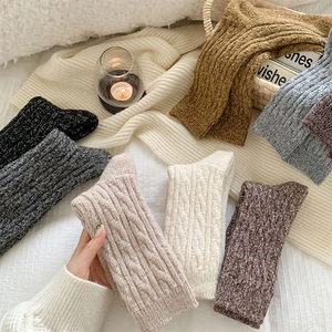 Detailed cable knit pattern on thick winter wool socks in various warm earthy tones