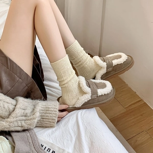 Close-up of brown suede slippers with white faux fur lining and knitted socks detail