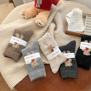 Detail of five pairs of wool socks featuring cute bear patterns on a warm knitted blanket