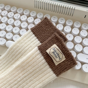 Vue détaillée de chaussettes en laine tricotées crème et marron avec étiquette