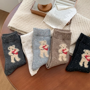 Detail showing five pairs of thick wool socks with cute teddy bear embroidery in neutral tones
