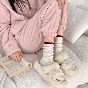 Gros plan de pantoufles beiges en fausse fourrure avec des chaussettes en tricot