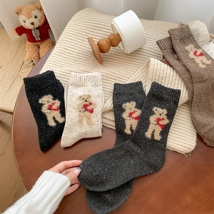 Close-up of wool knit socks with cute bear embroidery in four warm autumnal colors