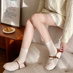 Detail of warm off-white wool socks and Mary Jane shoes in a cozy home setting