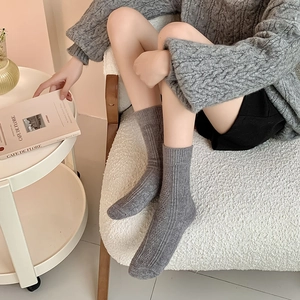 Detailed knit texture of dark grey thick wool socks in a cozy indoor home setting
