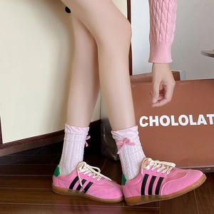 Detailed close-up of pink suede sneakers with side stripes and matching bow socks
