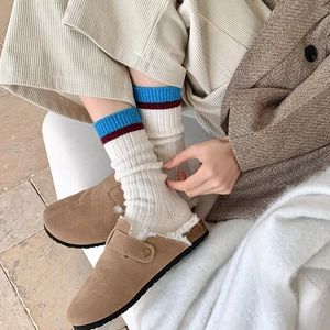 Détail de mules en daim marron avec doublure polaire et chaussettes rayées en maille