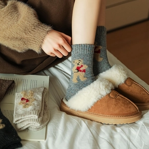 Detail of warm brown suede slippers with white plush lining and grey bear pattern socks
