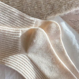 Close-up of cream vertical stripe wool knit socks showing soft thick texture and warmth