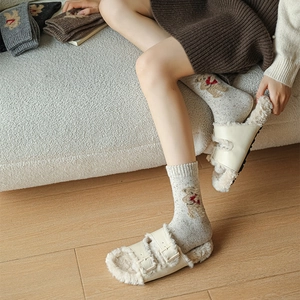 Detail of wool socks with bear embroidery paired with fuzzy double-buckle slippers