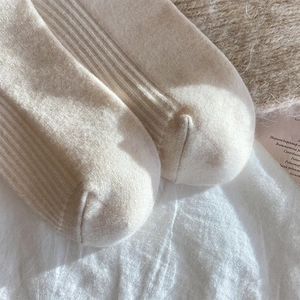 Close-up of cream white wool socks showing soft vertical rib knit texture and toe seam