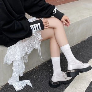 Detail of white platform loafers with bow-accented socks and metallic heel decor