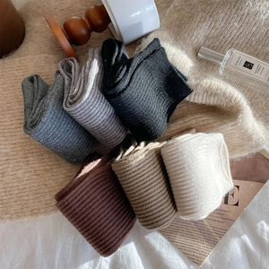 Close-up of thick ribbed wool socks in assorted earth tones on a cozy knit blanket