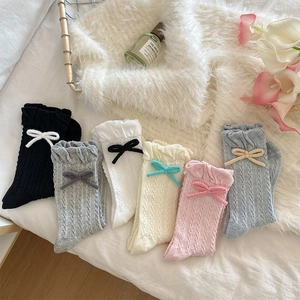 Detail of knit crew socks with ruffled cuffs and delicate ribbon bow decorations