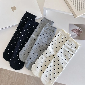Détail de chaussettes à pois avec bords à volants en couleurs noir gris et blanc
