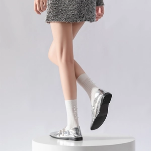 Detail of silver metallic loafers paired with white ribbed socks and side bow accents