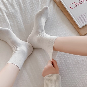 Detail view of high elasticity white ribbed cotton socks being stretched by hand