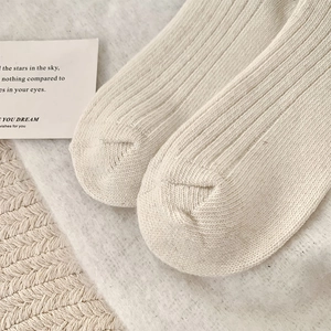 Gros plan de chaussettes en maille côtelée beige montrant la couture et la laine douce