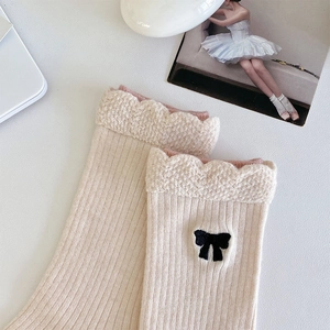 Gros plan de chaussettes en laine beige avec bordure en dentelle et noeud noir chic