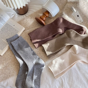 Detail view of thick ribbed wool socks in four colors on cozy bedding background