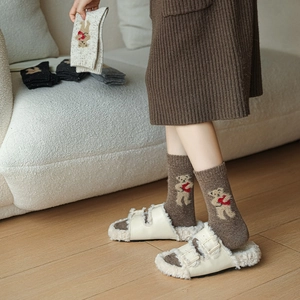 Detailed knit texture of wool socks featuring cute cartoon bear pattern and heart embroidery